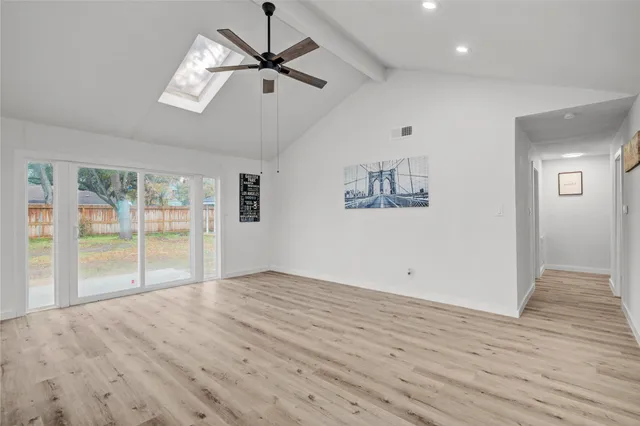 an empty room with wooden floor fan and windows