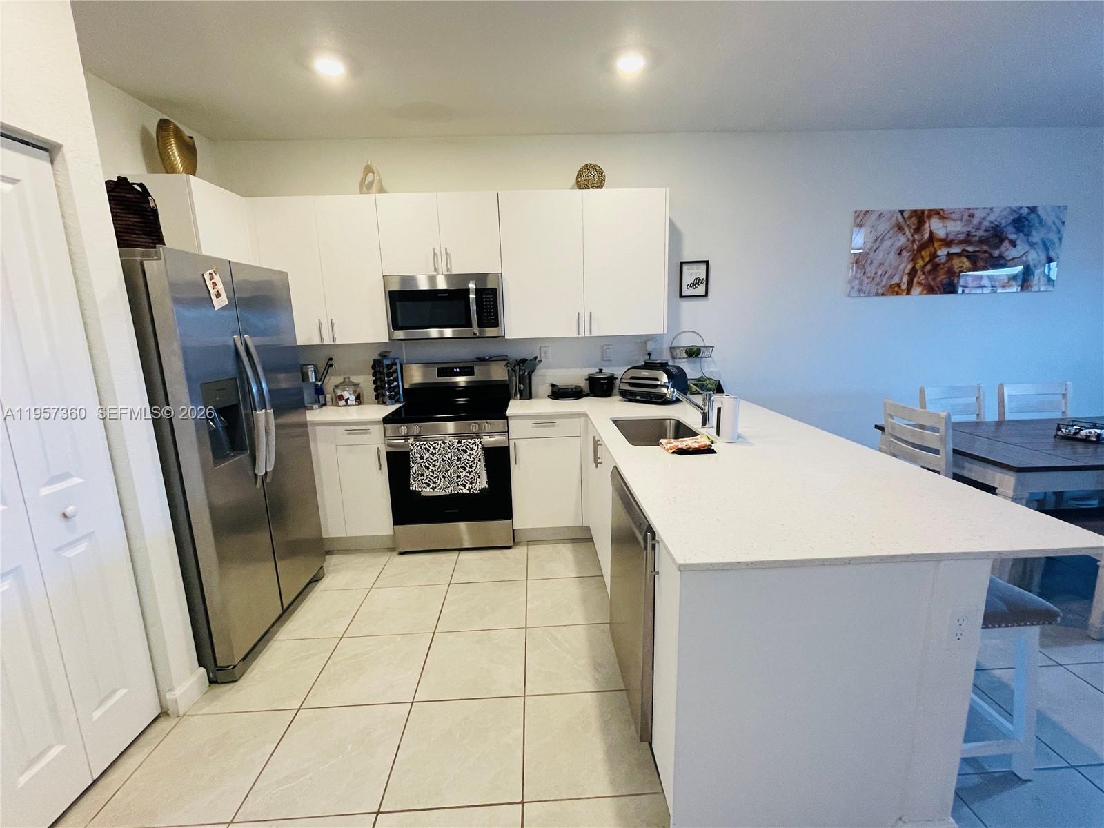 23153 Southwest 128th Place Miami, FL 33177 - Photo 16 of 22 a kitchen with a sink a refrigerator a stove a washer dryer and a dining table