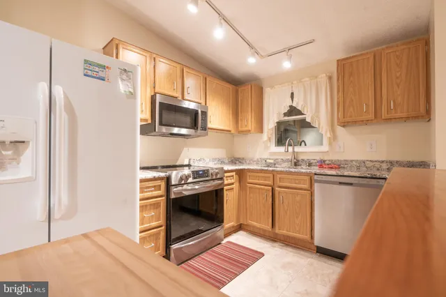 a kitchen with stainless steel appliances granite countertop a stove a sink dishwasher a refrigerator and a microwave