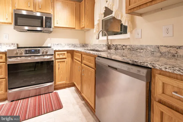 a kitchen with granite countertop a sink stove and microwave