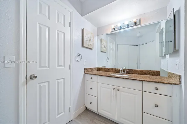 a bathroom with a granite countertop double vanity sink a mirror and a