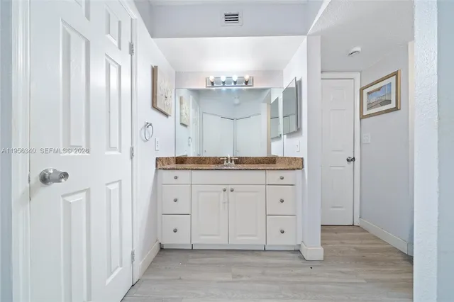 a spacious bathroom with a granite countertop sink and a mirror