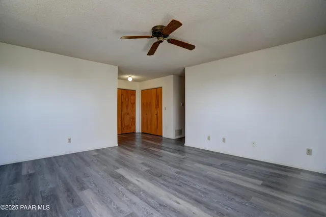 an empty room with windows and fan