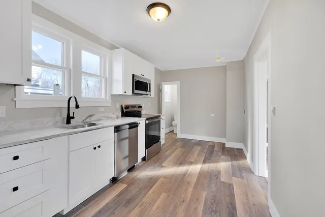 a kitchen with granite countertop a sink cabinets and stainless steel appliances