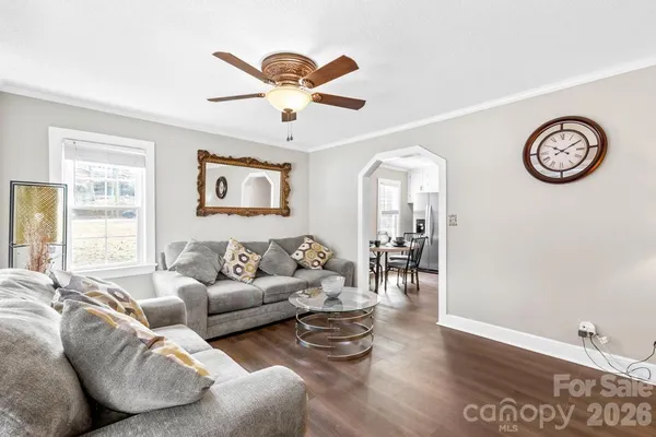 a living room with furniture a large window and wooden floor
