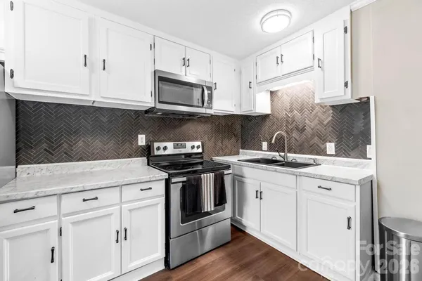 a kitchen with stainless steel appliances granite countertop white cabinets a sink and dishwasher