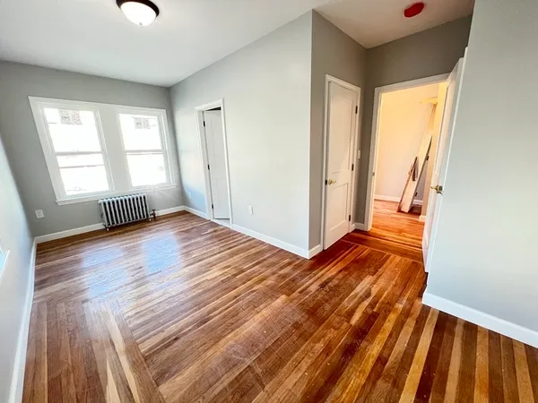 a view of an empty room with glass door and wooden floor