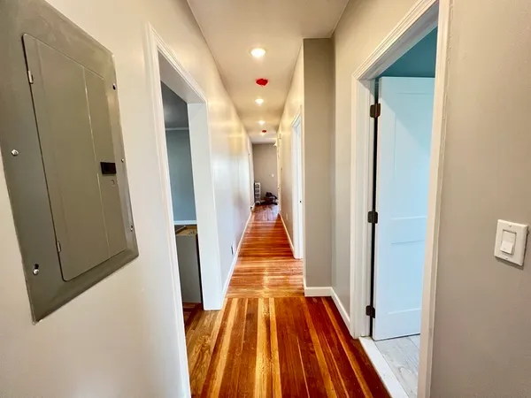 a view of a hallway with wooden floor and a bathroom