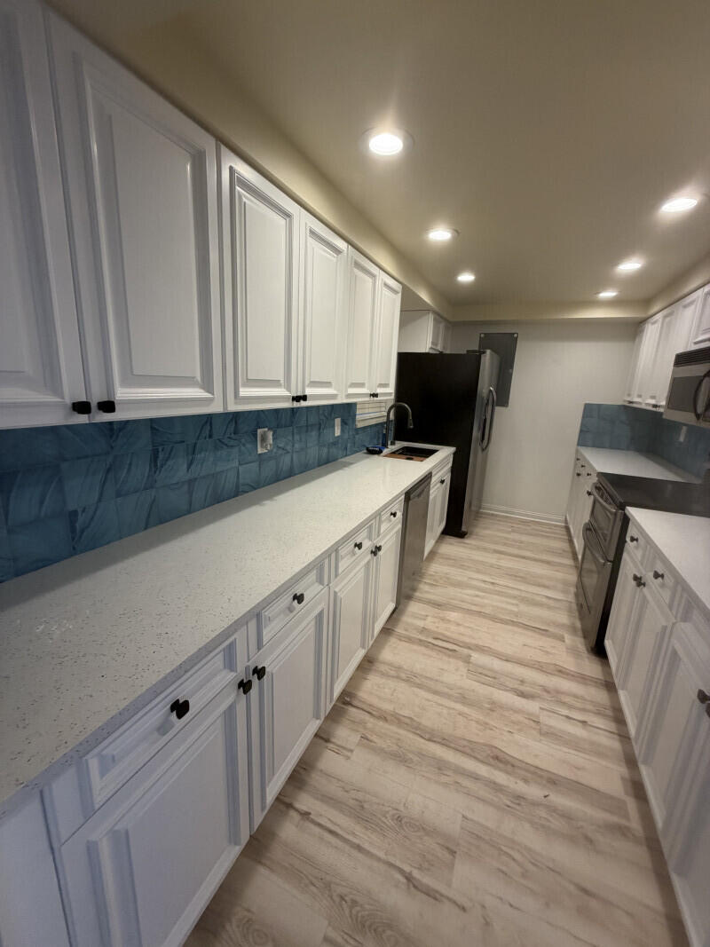1401 South Federal Highway, Unit 102 Boca Raton, FL 33432 - Photo 7 of 38 a large white kitchen with wooden floors and white stainless steel appliances