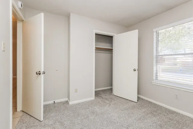 a view of an empty room with window and closet area