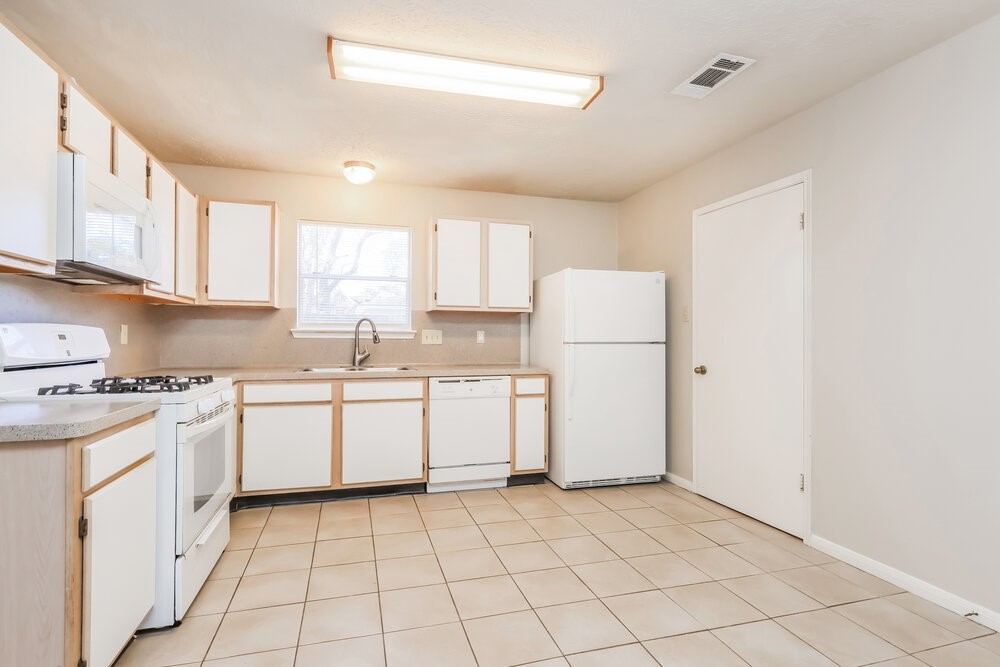 28907 Binefield Street Spring, TX 77386 - Photo 9 of 16 a kitchen with a sink a stove a refrigerator and white cabinets