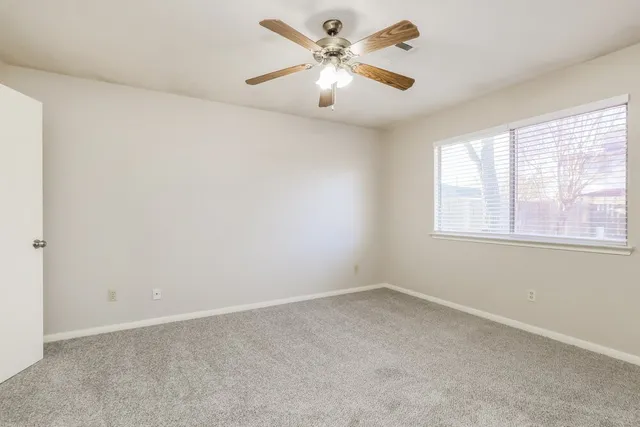 an empty room with a window and a fan