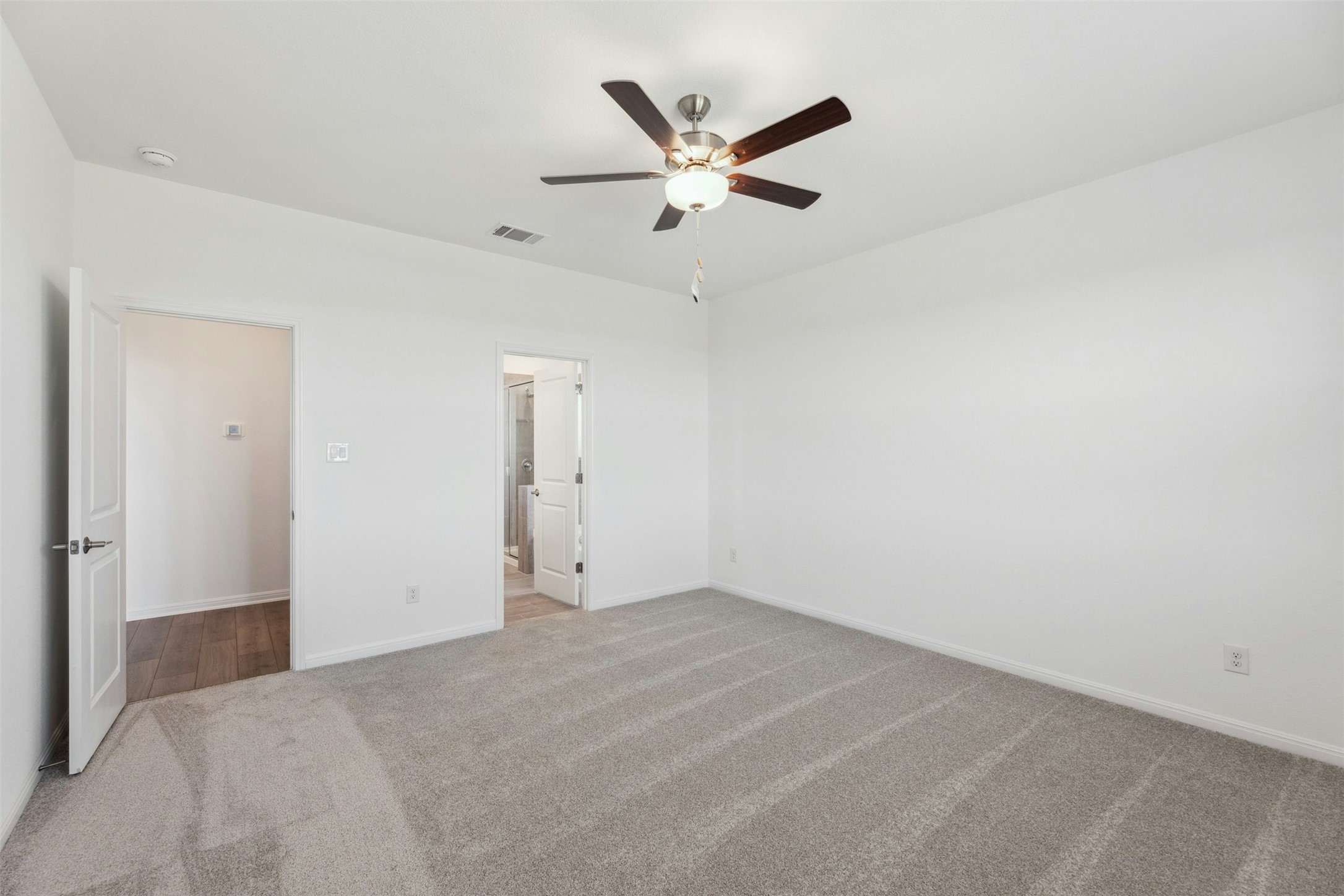 2001 Wynn Road Hutto, TX 78634 - Photo 13 of 39 A spacious bedroom features soft gray carpeting and a modern ceiling fan, offering a neutral canvas for personalization.