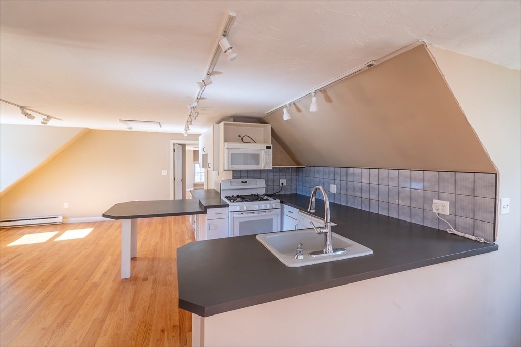 956 Bay Road, Unit 3 Hamilton, MA 01982 - Photo 5 of 30 a kitchen with kitchen island a sink and a stove with wooden floor