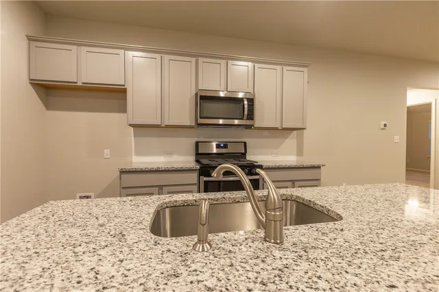 a kitchen with granite countertop a stove a sink and a refrigerator