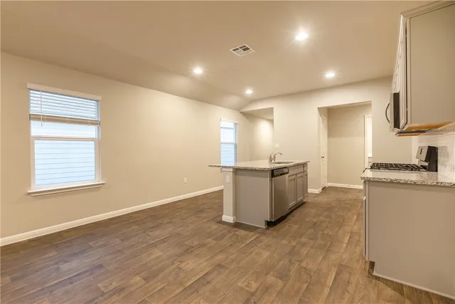 a kitchen with stainless steel appliances granite countertop a sink a stove top oven a granite counter tops and a white cabinets