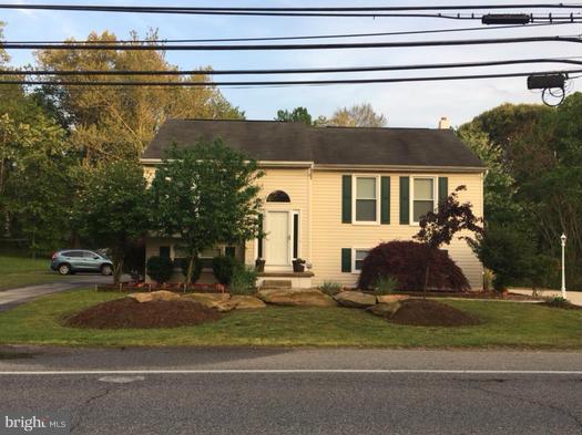 a view of a house with a cars park side of a road