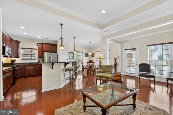 a living room with lots of furniture and kitchen view with wooden floor
