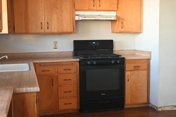 a kitchen with granite countertop a stove and a wooden cabinets