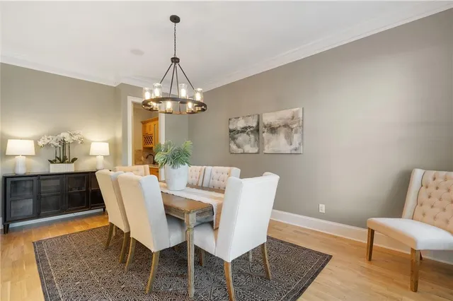 a kitchen with stainless steel appliances granite countertop a refrigerator a sink dishwasher a stove and a dining table with wooden floor