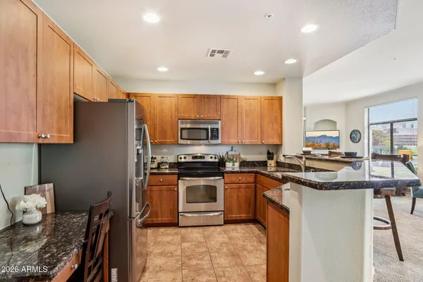 a kitchen with stainless steel appliances granite countertop a stove top oven a sink a refrigerator and white cabinets