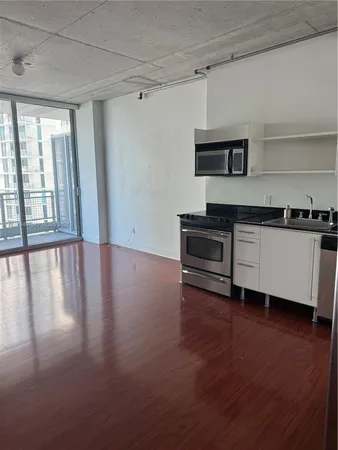 a kitchen with stainless steel appliances a stove a sink a microwave and wooden floor