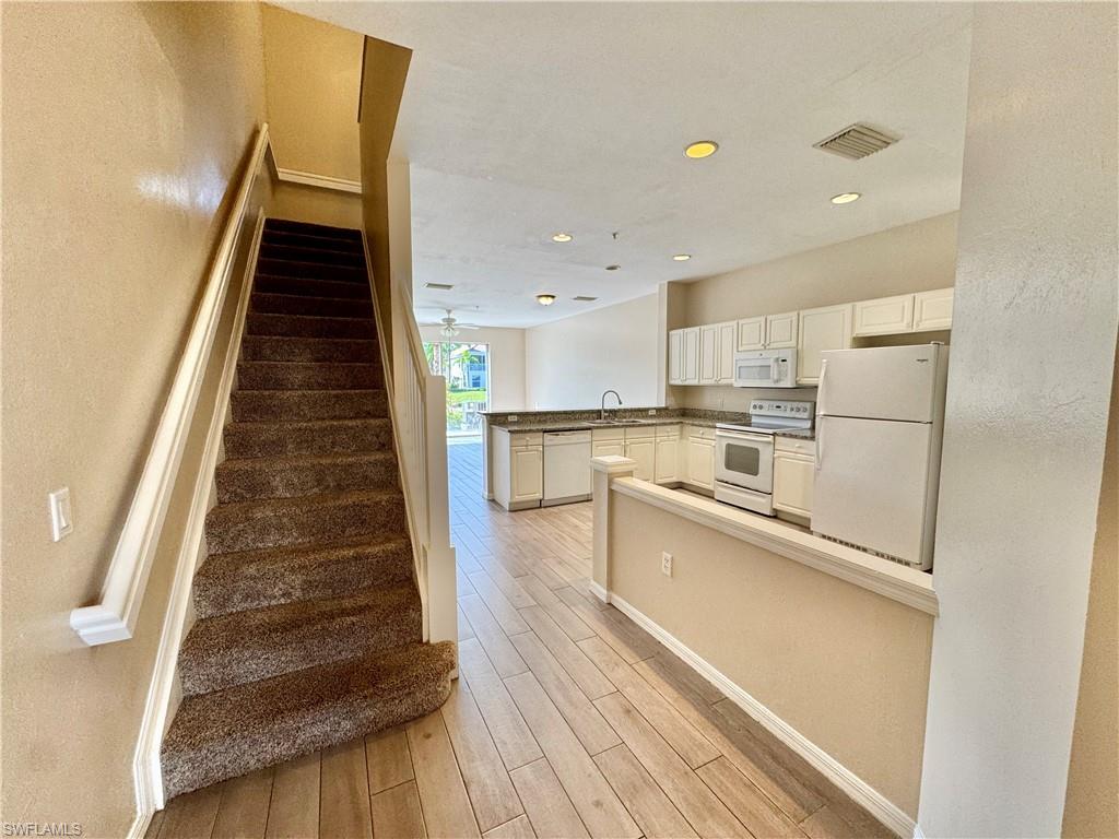912 Hampton Circle, Unit 92 Naples, FL 34105 - Photo 1 of 31 Stairway featuring wood finished floors, recessed lighting, and a textured wall