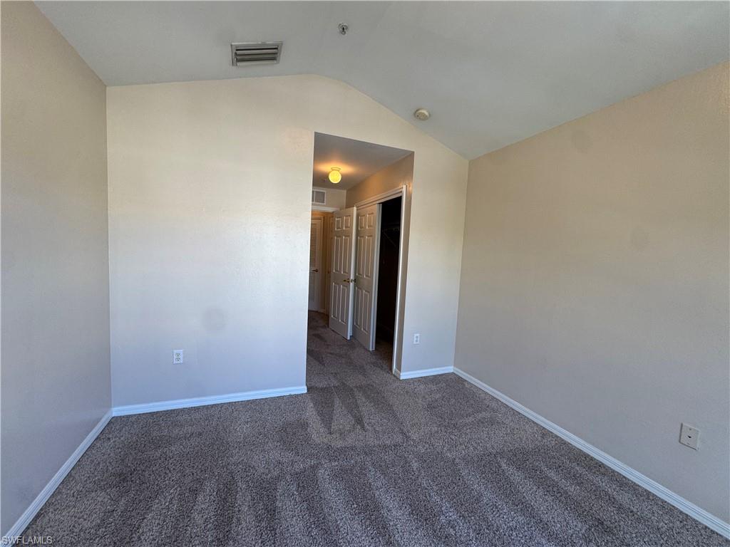 912 Hampton Circle, Unit 92 Naples, FL 34105 - Photo 22 of 31 Spare room featuring dark carpet and lofted ceiling