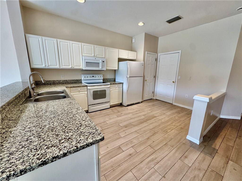 912 Hampton Circle, Unit 92 Naples, FL 34105 - Photo 3 of 31 Kitchen featuring dark stone countertops, white appliances, white cabinets, light wood finished floors, and recessed lighting