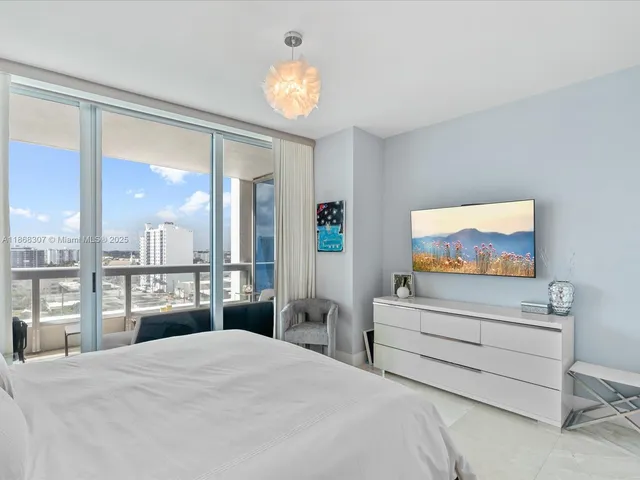 a bedroom with a bed and a large mirror on the dresser