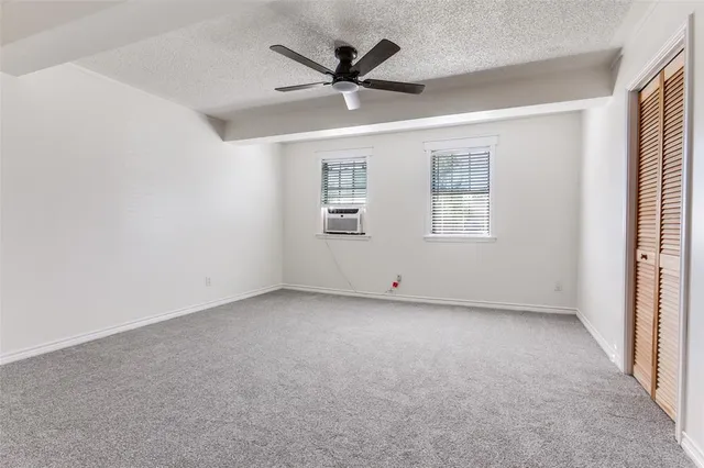 an empty room with windows and ceiling fan