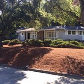 a front view of a house with yard and large trees