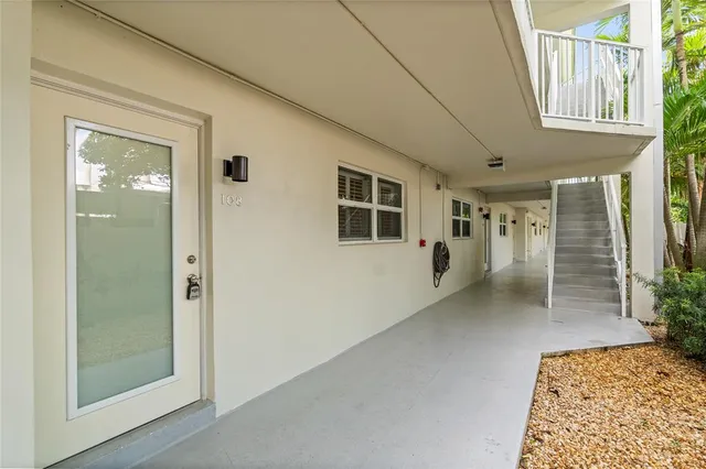 a view of an empty room with a window and kitchen view