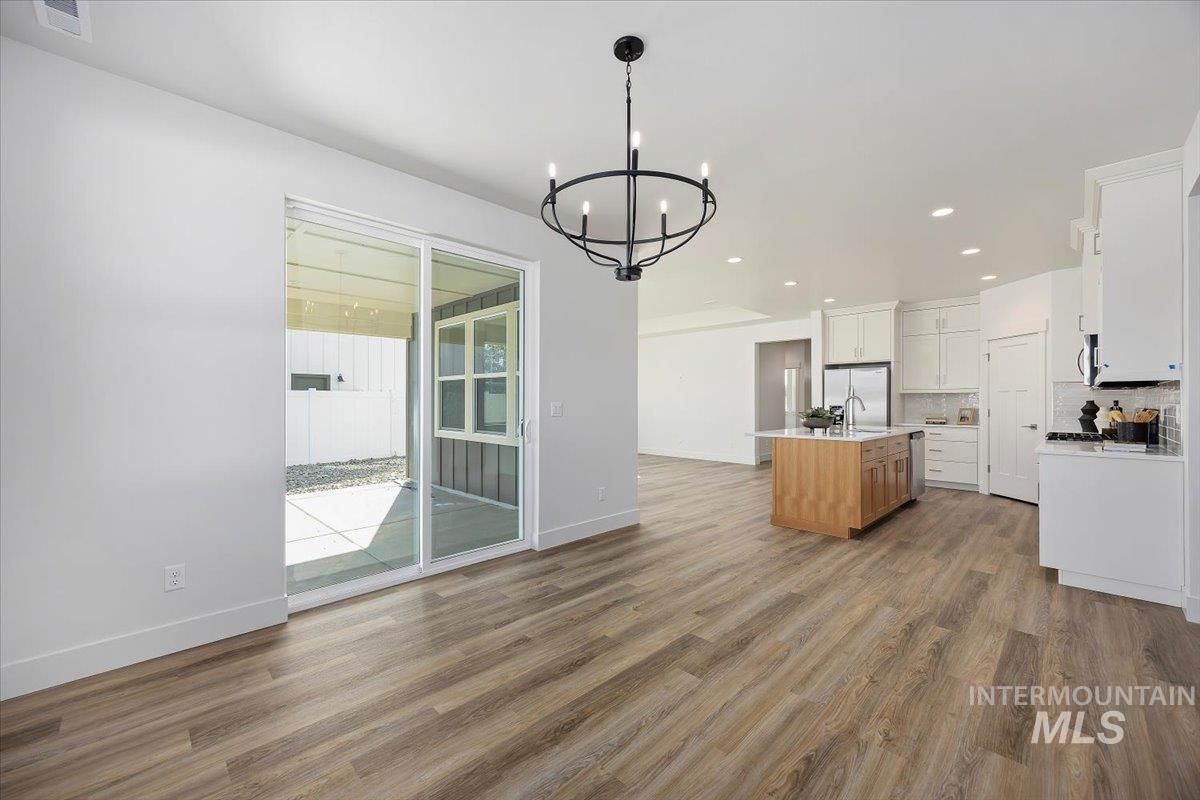 178 Maxine Lane, Unit HOMESITE 204 Kimberly, ID 83341 - Photo 23 of 24 Kitchen featuring light wood-style flooring, white cabinetry, decorative backsplash, open floor plan, and recessed lighting