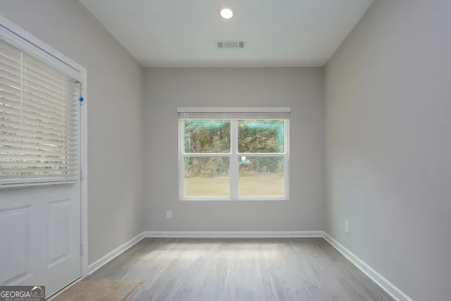 an empty room with wooden floor and windows