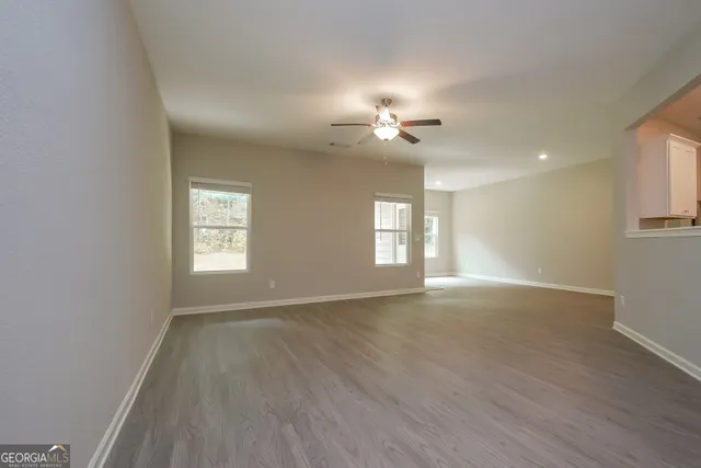 a view of an empty room with a window and wooden floor
