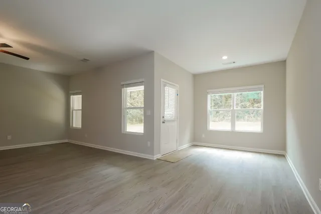 an empty room with wooden floor and windows