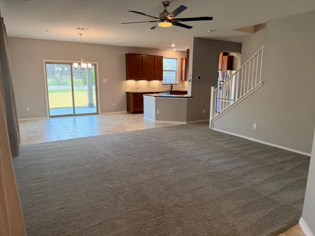a view of a refrigerator in kitchen and an empty room with wooden floor