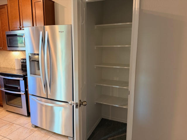 329 Los Cobos Lane Georgetown, TX 78626 - Photo 14 of 40 a view of a refrigerator in kitchen and an empty room with wooden floor