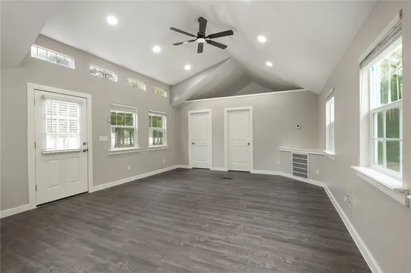 an empty room with wooden floor and windows