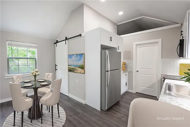 a kitchen with stainless steel appliances kitchen island granite countertop a refrigerator a sink dishwasher a dining table and chairs with wooden floor
