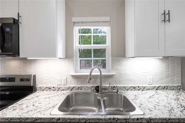 a kitchen with granite countertop a sink a stove and cabinets