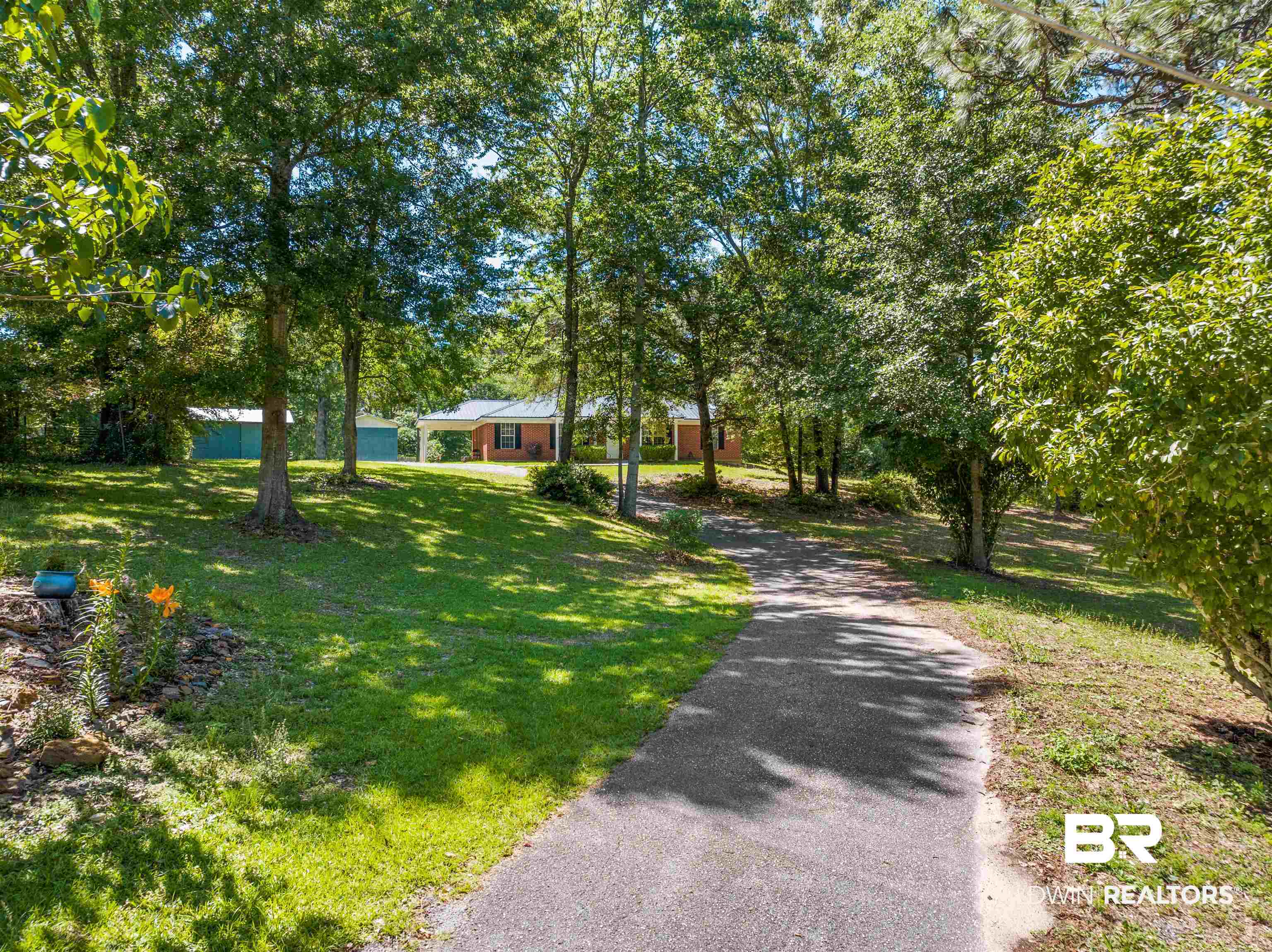 35893 Pine Road South Stapleton, AL 36578 - Photo 4 of 31 Paved driveway ascending to a brick residence with a covered carport, surrounded by mature trees and manicured lawns
