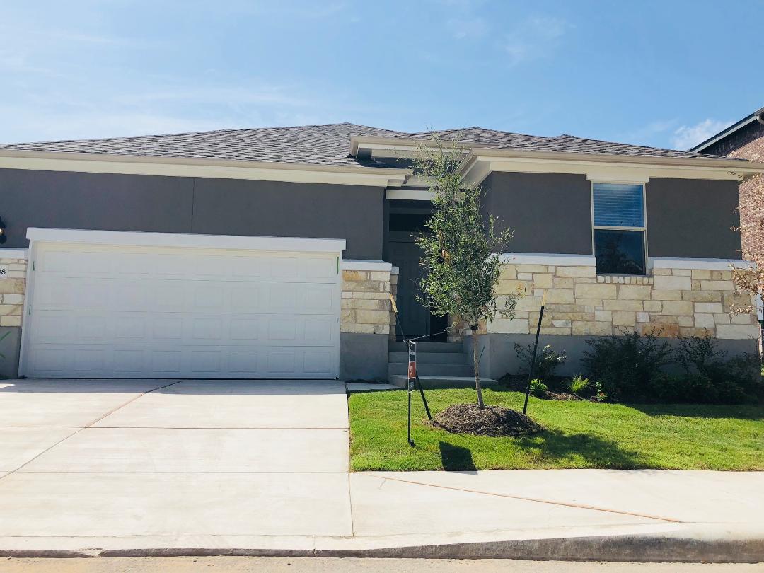 Prairie-style house with stone siding, driveway, a front yard, and stucco siding