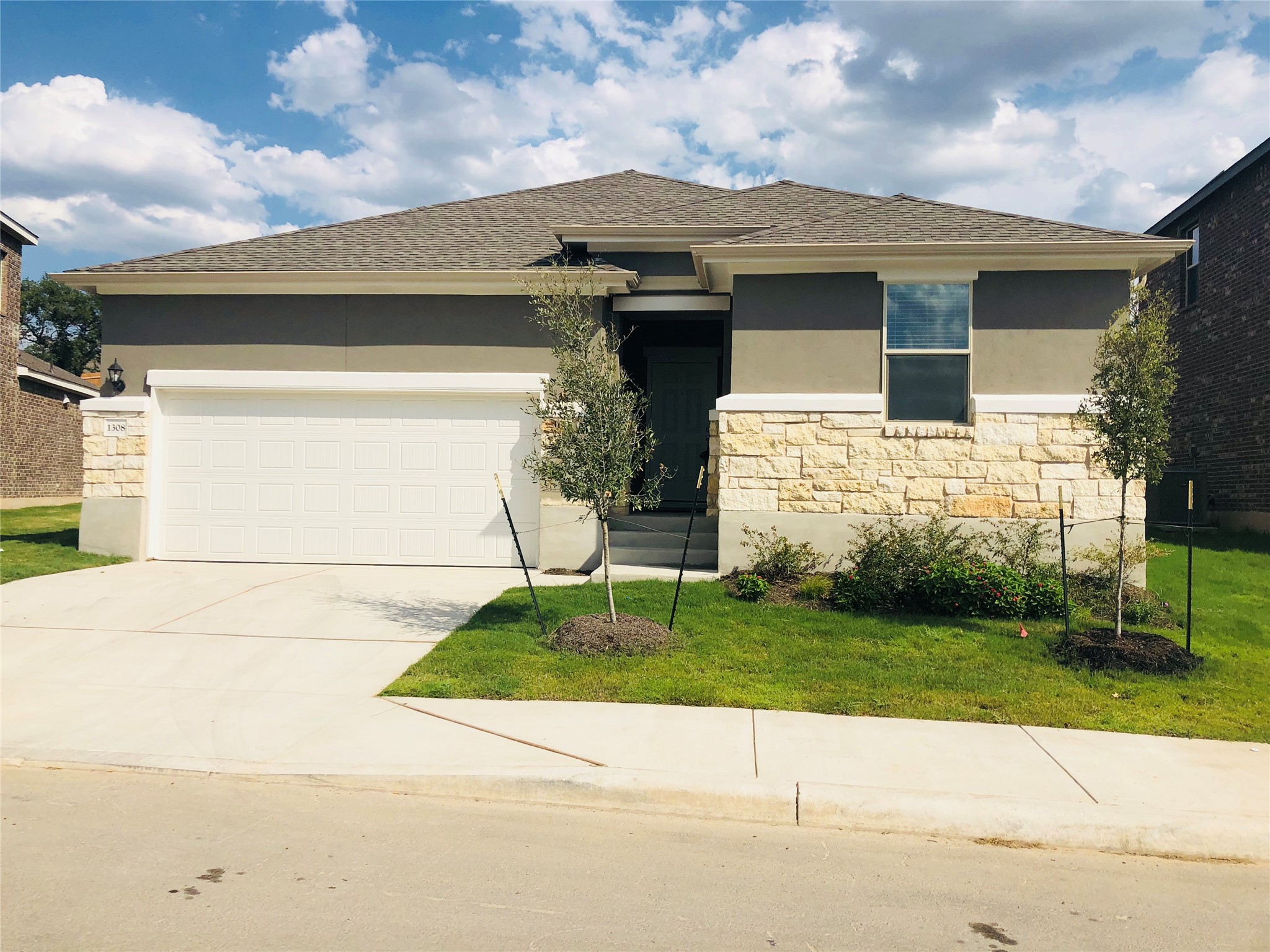 1308 Eagle Ridge Trail Leander, TX 78641 - Photo 2 of 16 View of front facade featuring stucco siding, roof with shingles, driveway, stone siding, and a garage