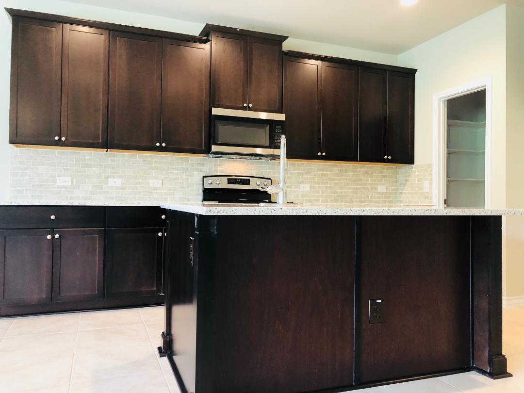 1308 Eagle Ridge Trail Leander, TX 78641 - Photo 5 of 16 Kitchen with stainless steel appliances, tasteful backsplash, light tile patterned floors, and light stone countertops