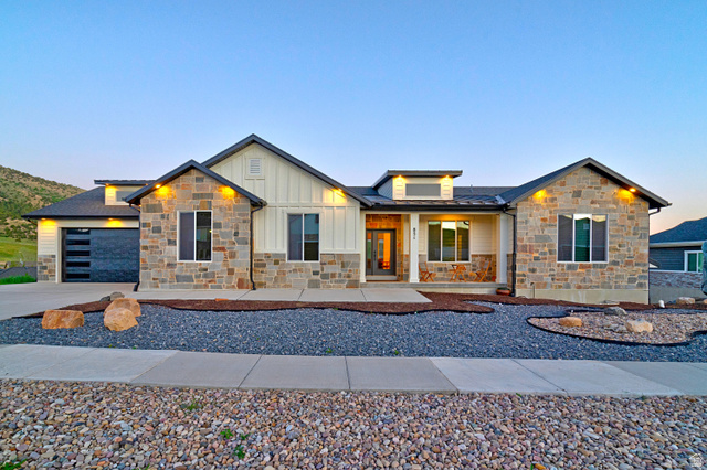 851 Grandview Drive Morgan, UT 84050 - Photo 2 of 68 Contemporary ranch-style exterior featuring a stone and board-and-batten facade, a modern garage door, and a low-maintenance gravel and rock landscape