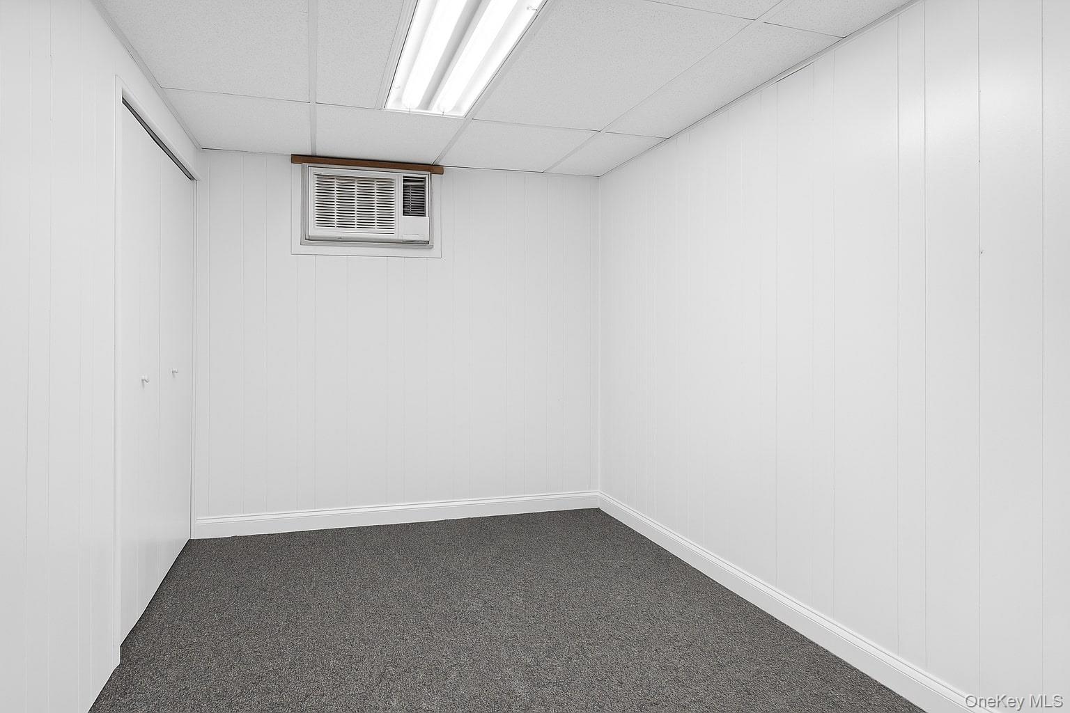 7 Judith Street Plainview, NY 11803 - Photo 33 of 45 Finished basement with dark colored carpet, a drop ceiling, and a wall unit AC