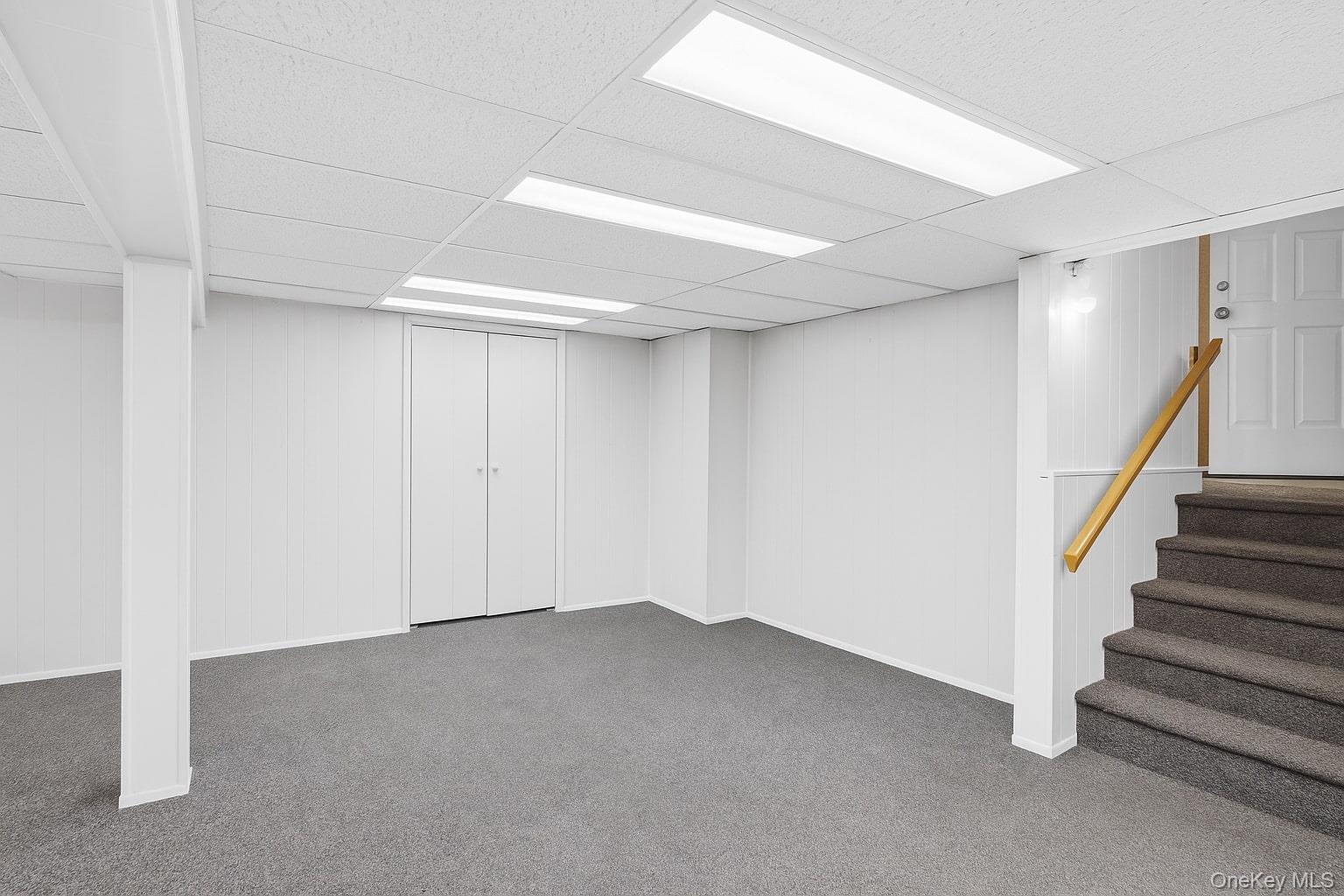 7 Judith Street Plainview, NY 11803 - Photo 34 of 45 Finished basement with a drop ceiling, carpet, wooden walls, and stairway