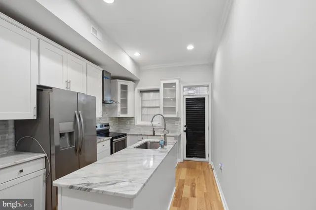 a kitchen with granite countertop a refrigerator a sink a stove and cabinets